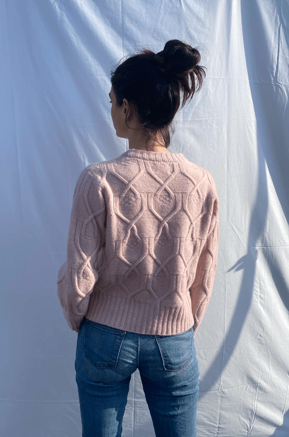 Woman wearing a pink cable knit sweater back view
