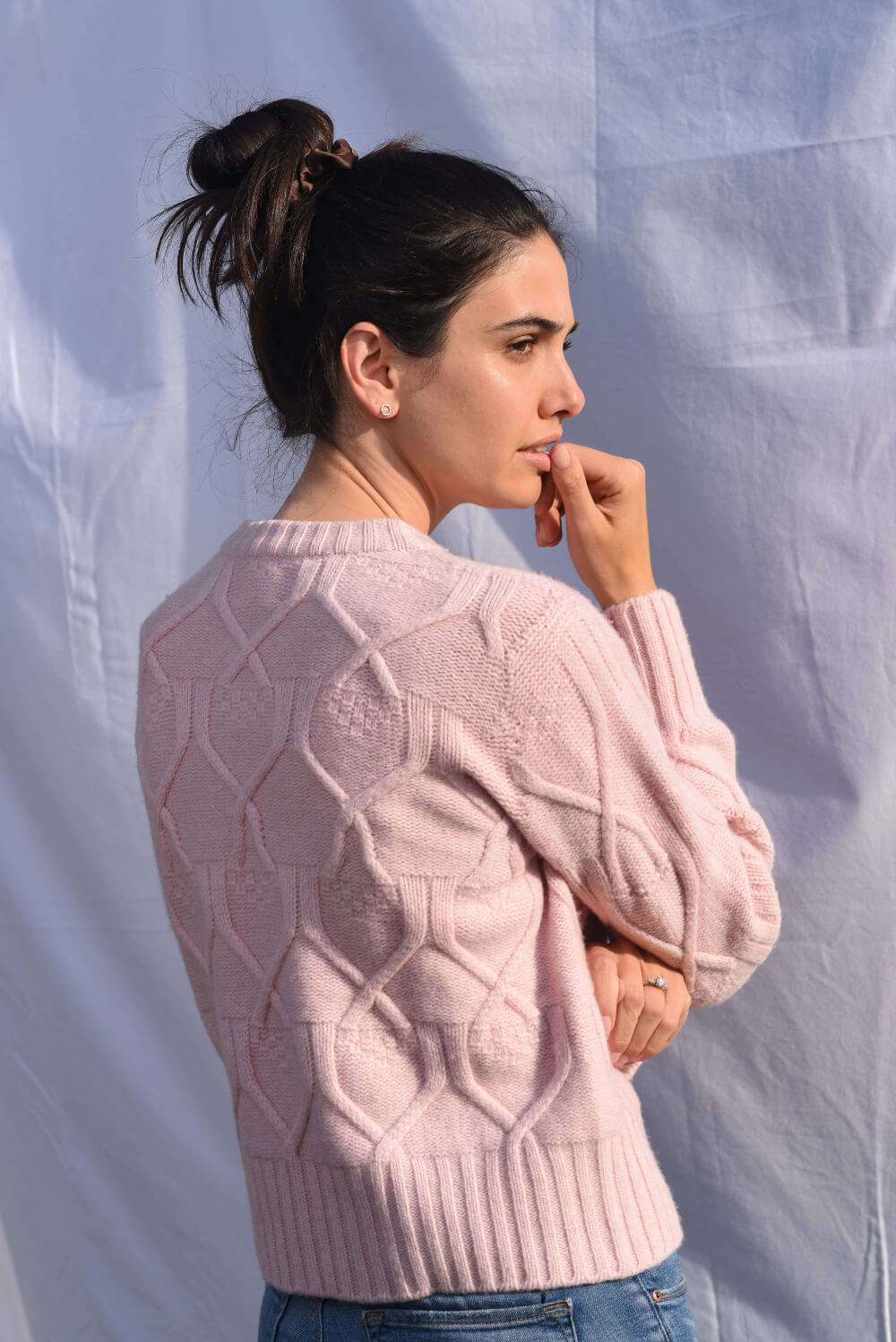 Woman wearing a light pink cable knit sweater