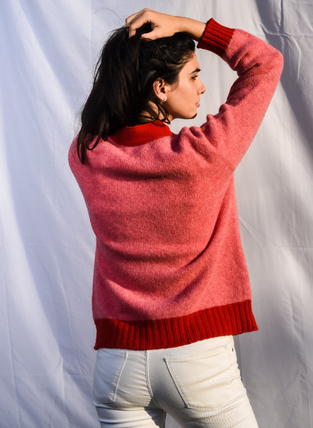 Woman wearing a pink cardigan with a red trim view from back