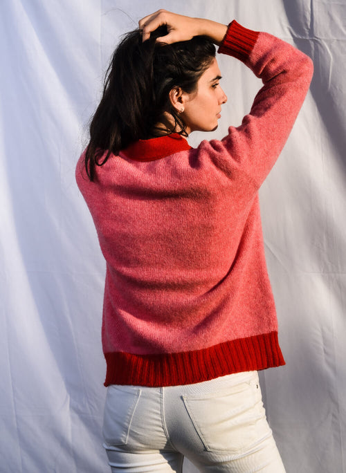 Woman wearing a pink cardigan with a red trim view from back