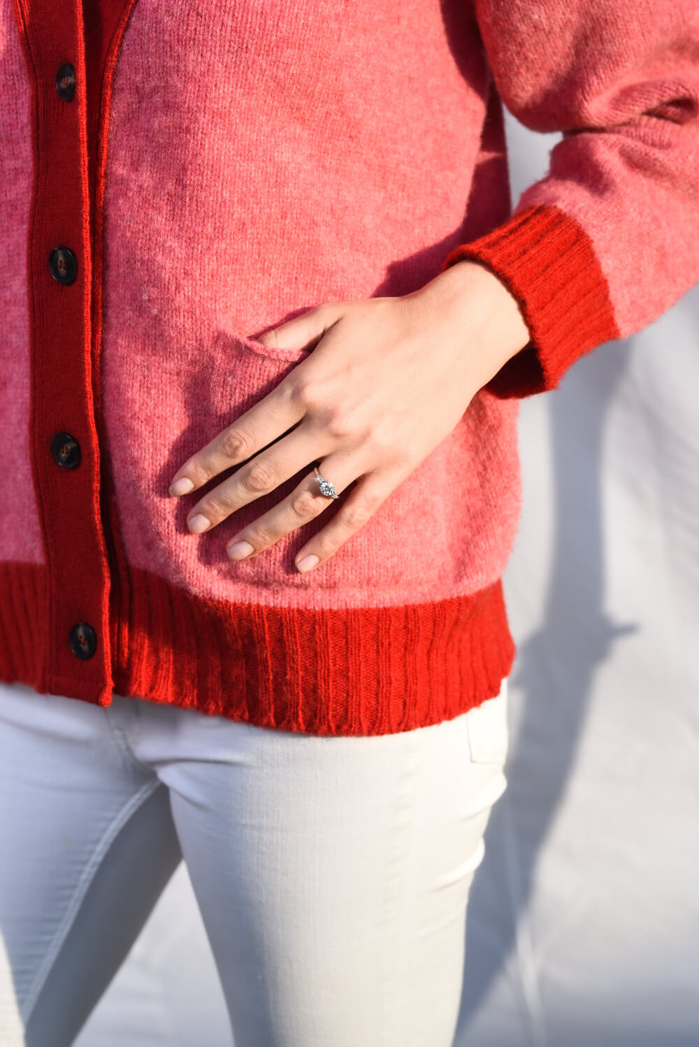 Pink cardigan with red trim placket and pocket close up
