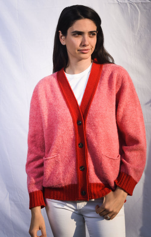 Woman wearing a pink knitted cardigan with red placket cuffs and hem