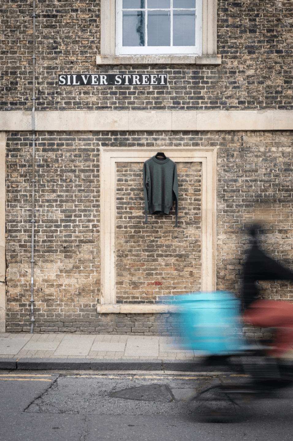 Merino wool crew neck jumper hanging against brick wall